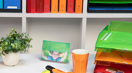 Schreibtisch und Regal mit verschiedenfarbigen Büroaccessoires von von Exacompta.