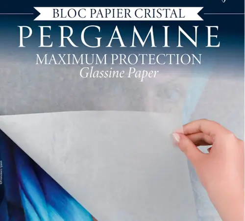 Eine Hand hebt ein dünnes Blatt durchscheinendes Pergaminpapier von einer bunten Fläche. Auf der Verpackung steht Bloc Papier Cristal Pergamine Maximum Protection Glassine Paper.